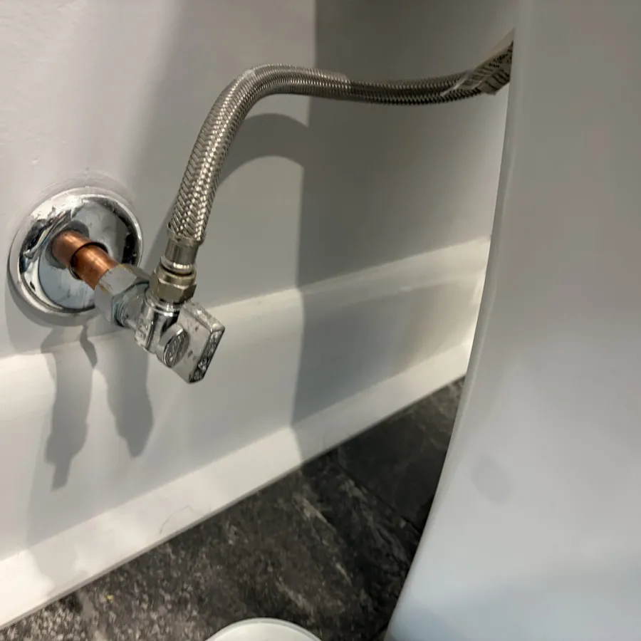 New chrome shutoff valve and braided supply line at a bathroom fixture